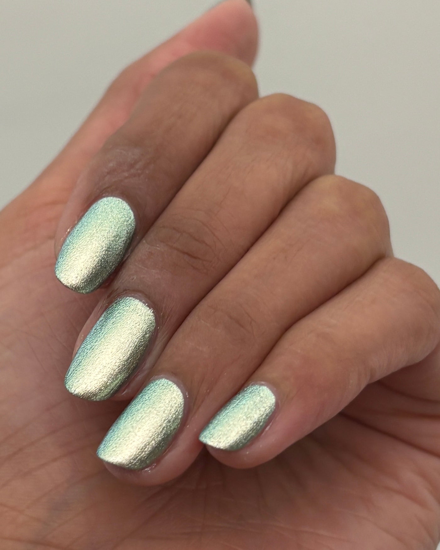 Atomica shimmering metallic mint green nail polish on hand