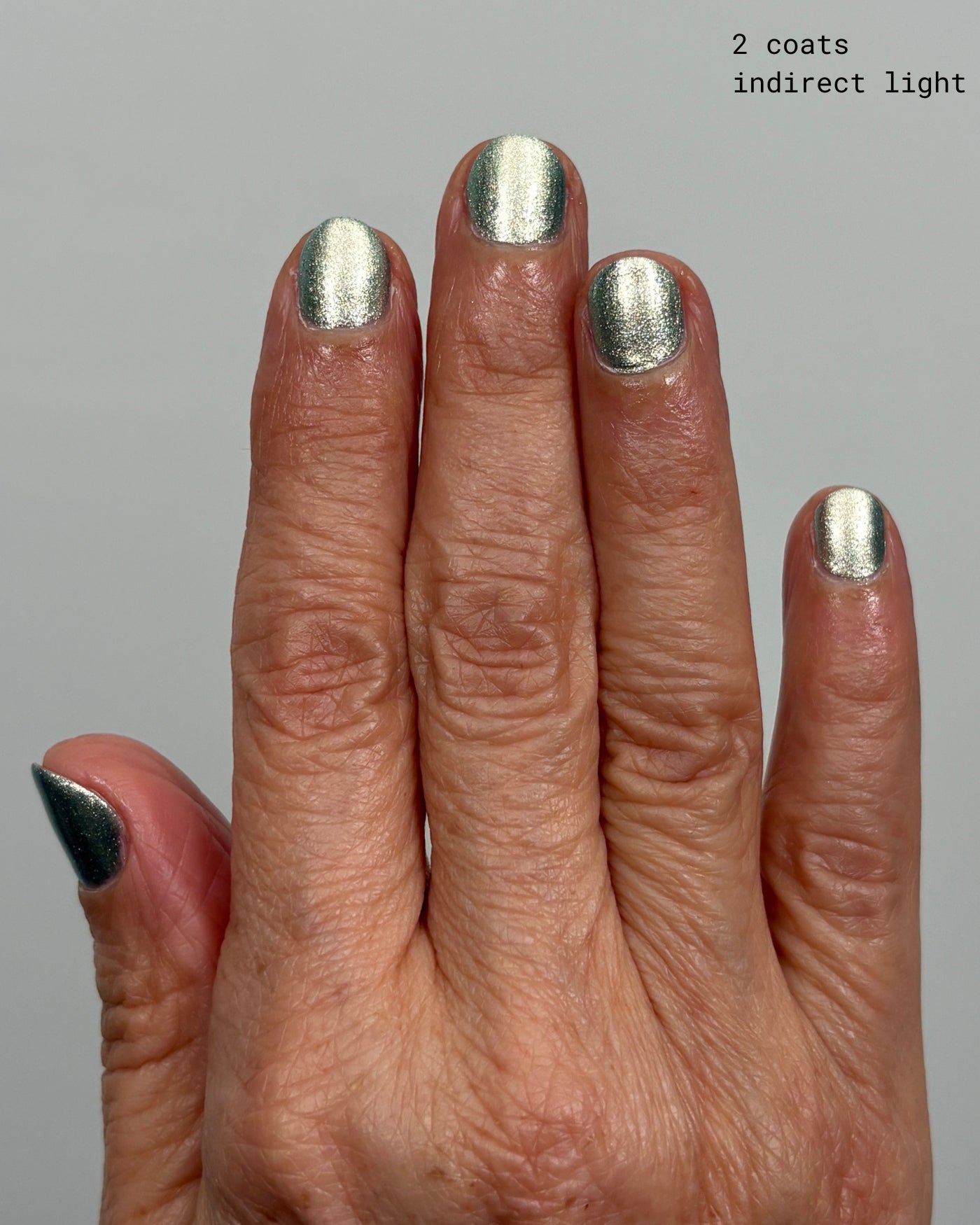 Shimmering Atomica silver nail polish in two coats under indirect light