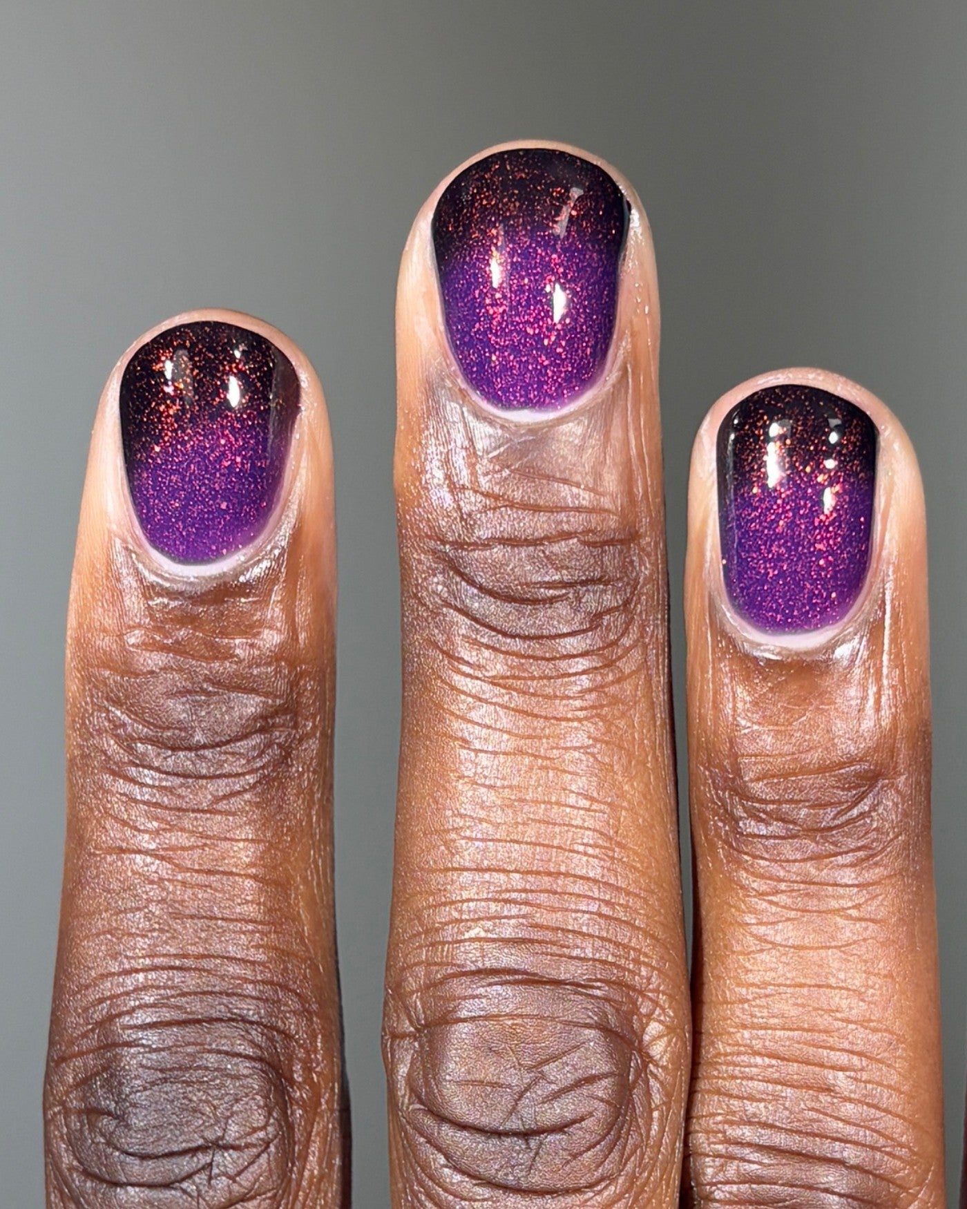 The Firebird purple gradient nail polish with glitter on three fingers