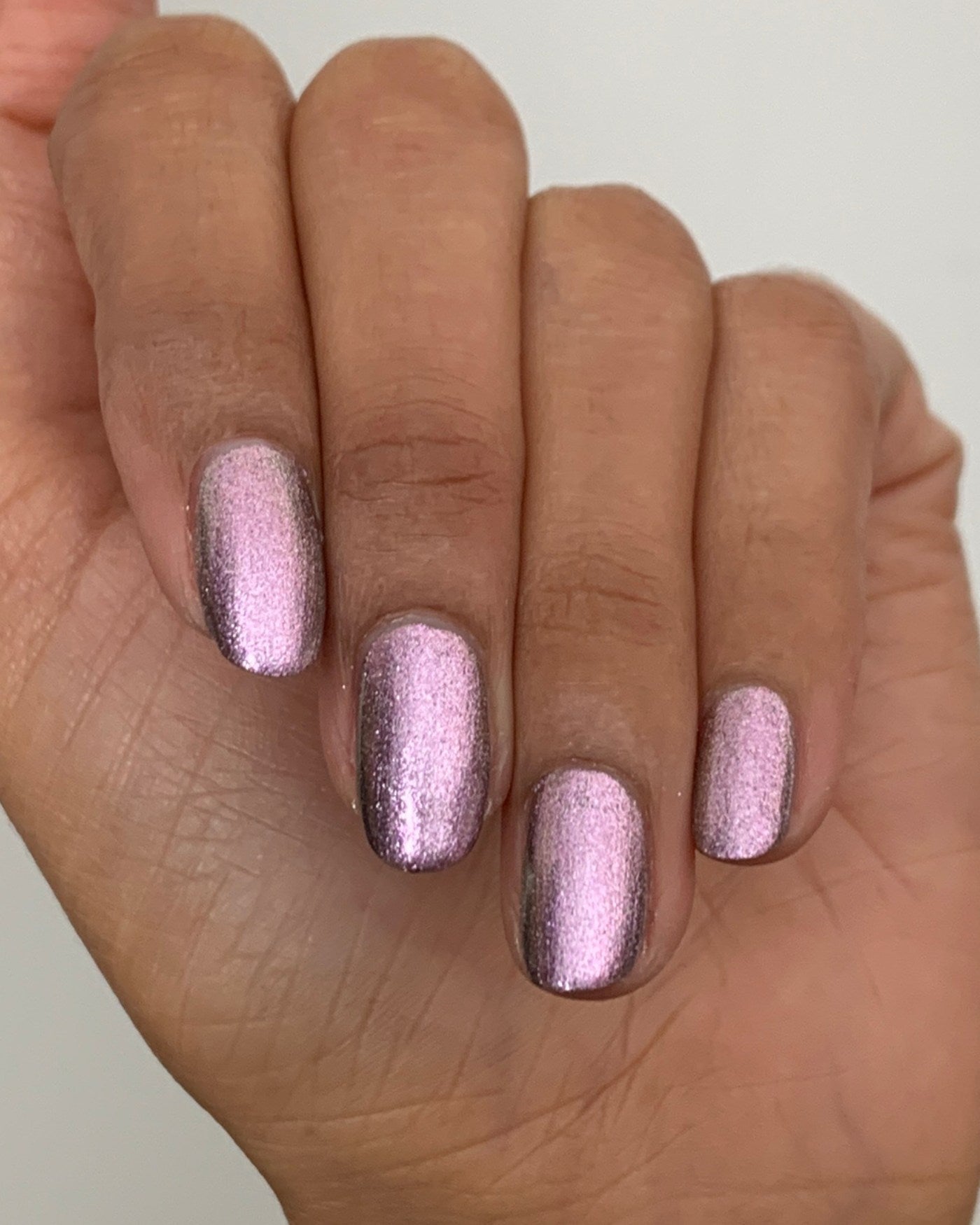 Nightbreak shimmering metallic rose gold nail polish on hand